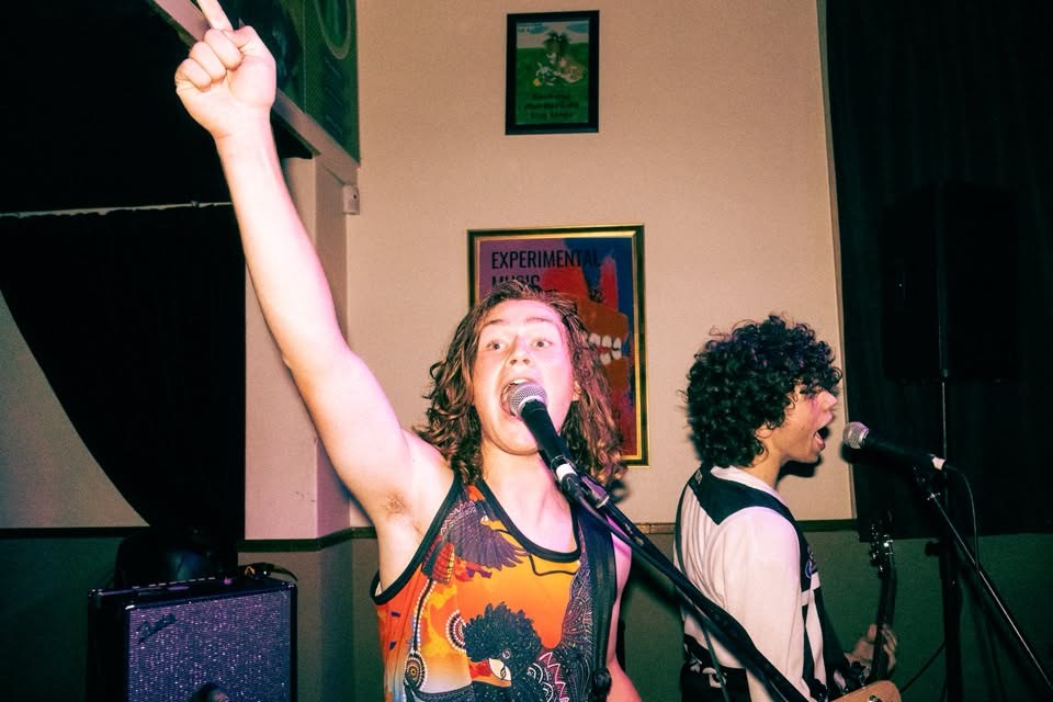 Will Fleming with his fist in the air, Nathan Ebbs singing behind